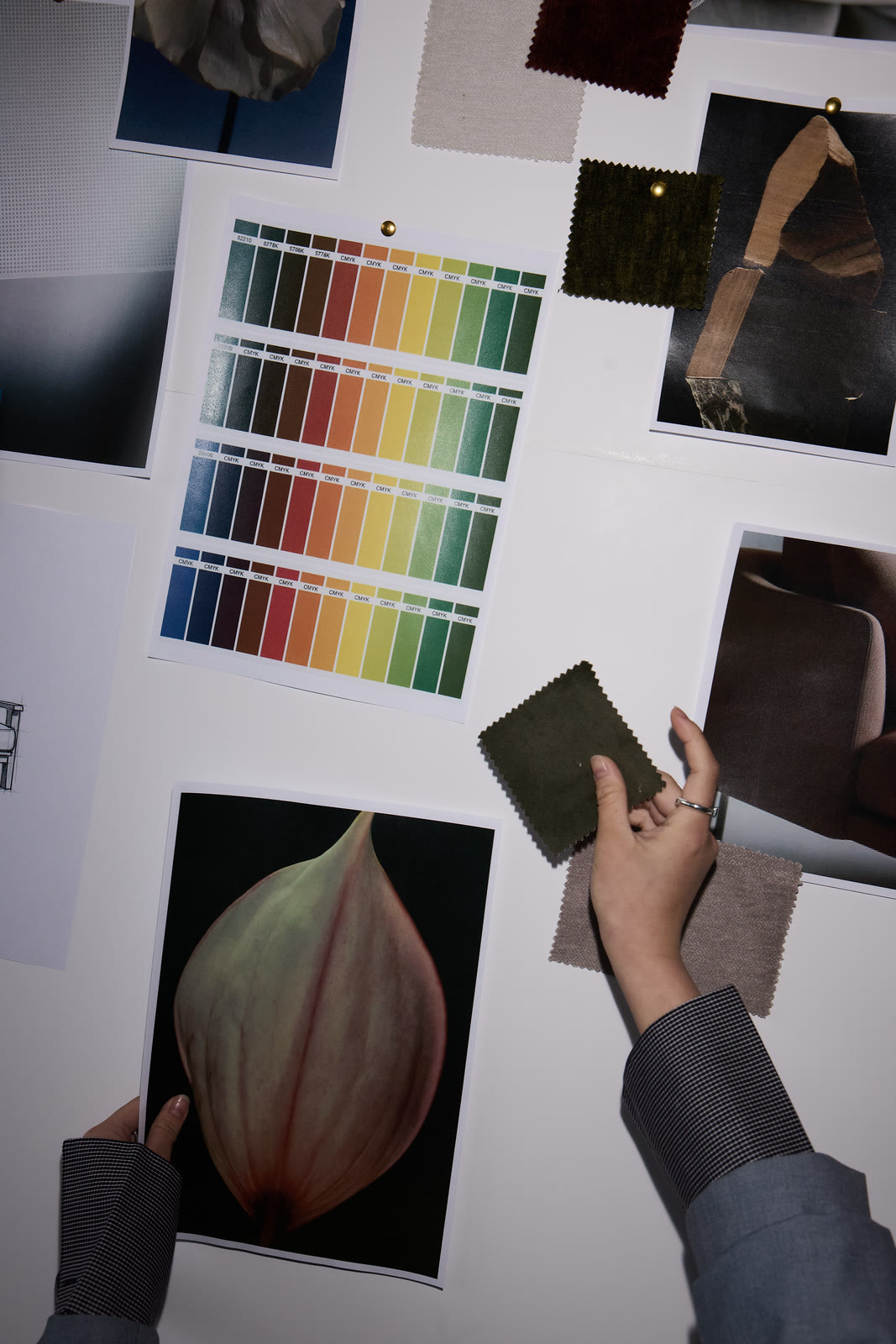 A designer arranging colour swatches on a studio moodboard wall