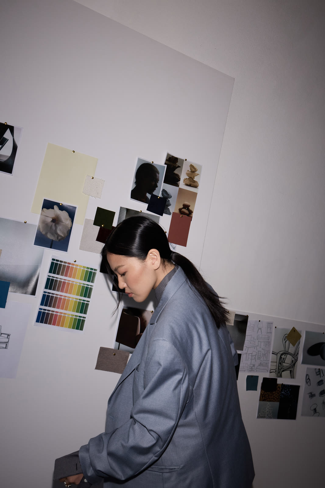A designer at work against a studio wall of colour swatches and moodboards