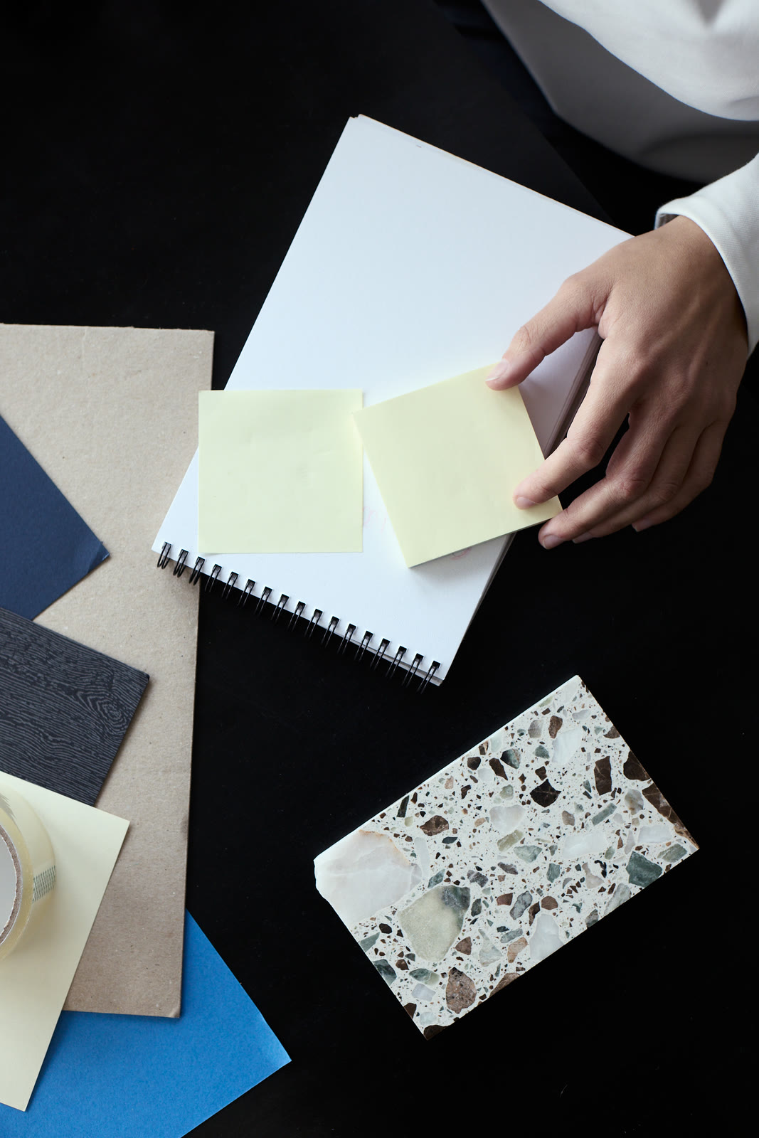 Hands holding paper samples over a spread of colour swatches